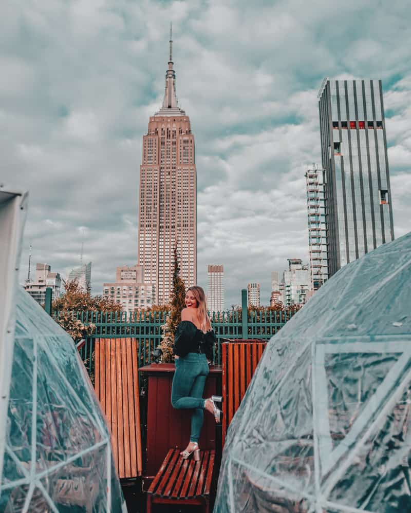 girl standing on roof in front of empire state building