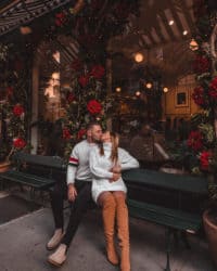 couple assis sur un banc devant une boutique qui s'embrasse