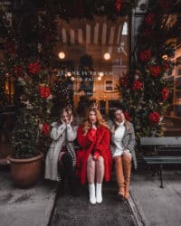 3 raparigas sentadas num banco à frente de uma boutique