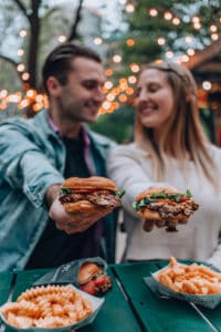 una pareja sosteniendo hamburguesas