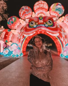 girl standing in front of an asian dragon lantern